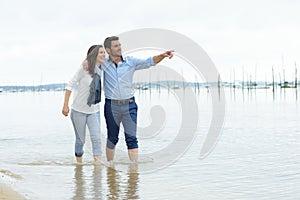 Portrait happy couple holding hands while walking on shore