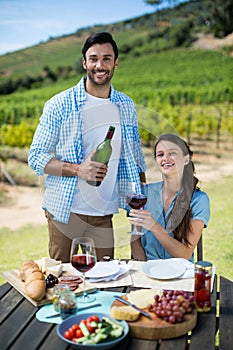 Portrait of happy couple holding red wine bottle and glass