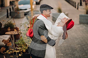 Portrait of a happy couple hugging on the street in an autumn city. Retro stylish couple in autumn in the city