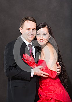 Portrait of happy couple in love posing at studio on gray background dressed in red.