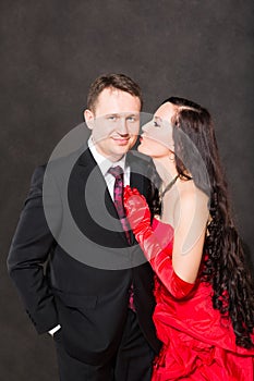 Portrait of happy couple in love posing at studio on gray background dressed in red.