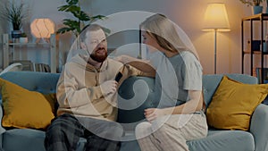 Portrait of happy couple in pajamas watching TV hugging smiling looking at camera in dark room