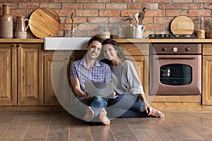 Portrait of happy couple relaxing in kitchen with laptop