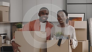 Portrait of happy couple smiling looking at camera holding paper boxes during relocation. Family lifestyle and housing