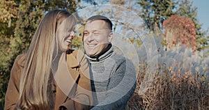 Portrait of a happy couple smiling and looking at the camera. Standing in warm clothes in the fall park