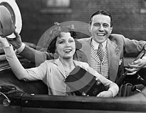 Portrait of happy couple waving in car