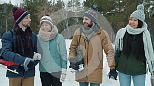 Portrait of happy couples men and women walking outdoors in park holding ice-skates talking