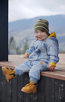 Portrait of a happy Cute children wearing blue overall sitting on patio outdoor