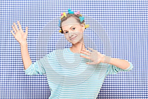 Portrait of happy cute girl with bright colorful hair curlers on head