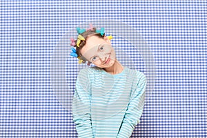 Portrait of happy cute girl with bright colorful hair curlers on head