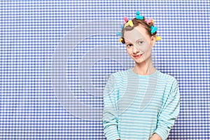 Portrait of happy cute girl with bright colorful hair curlers on head