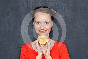 Portrait of happy cute girl holding half of lemon under head