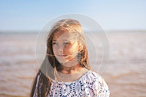 Portrait of Happy Cute Girl in During Summer Vacation On Exotic Tropical Beach. Wind in a hair. Family Journey