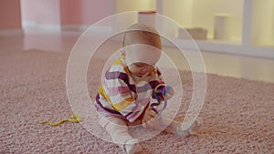 Portrait of happy cute infant baby sitting on floor and playing with toys