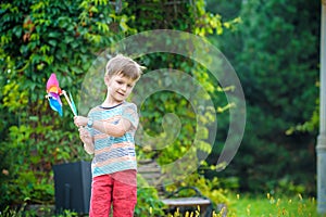 Portrait of a happy cute little boy holding pinwheel at the park. kid hold in hand play with windmill. boy smiling in spring or