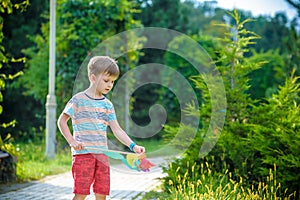 Portrait of a happy cute little boy holding pinwheel at the park. kid hold in hand play with windmill. boy smiling in spring or