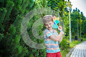 Portrait of a happy cute little boy holding pinwheel at the park. kid hold in hand play with windmill. boy smiling in spring or su