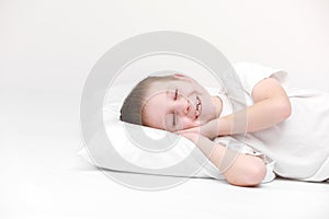 Portrait of a happy cute little boy waking up in the morning and lying on a white pillow isolated on a white background. fresh and