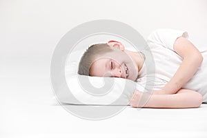 Portrait of a happy cute little boy waking up in the morning and lying on a white pillow isolated on a white background. fresh and