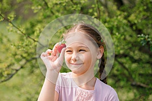 Portrait of Happy cute little girl is eating strawberries at summer day. Soft focused