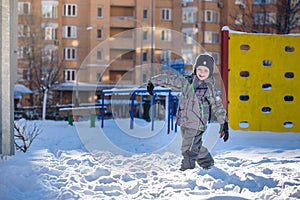 Portrait of happy cute little kid boy in colorful warm winter fashion clothes. Funny child having fun in forest or park on cold da