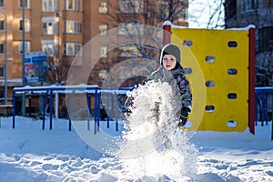 Portrait of happy cute little kid boy in colorful warm winter fashion clothes. Funny child having fun in forest or park on cold da