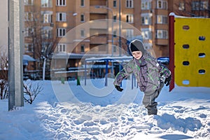 Portrait of happy cute little kid boy in colorful warm winter fashion clothes. Funny child having fun in forest or park on cold da