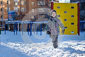 Portrait of happy cute little kid boy in colorful warm winter fashion clothes. Funny child having fun in forest or park on cold da