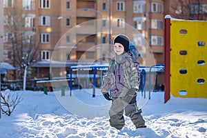 Portrait of happy cute little kid boy in colorful warm winter fashion clothes. Funny child having fun in forest or park on cold da