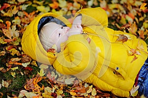 Portrait of happy cute toddler boy with autumn leaves background