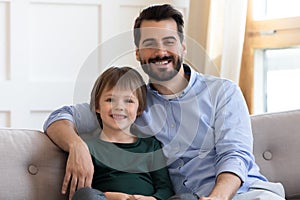 Portrait of happy dad and little son relax on couch