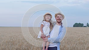 Portrait of happy daddy with kid girl, young man stays with cheerful smiling daughter on his hands looking at each other