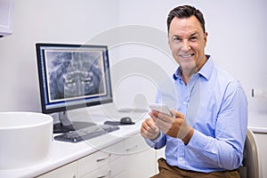 Portrait of happy dentist using mobile phone