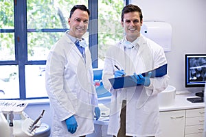Portrait of happy dentists standing with file photo