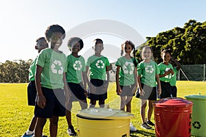Portrait of happy diverse children collecting recycling smiling in sunny elementary school field