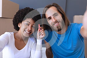 Portrait of happy diverse couple moving house sitting and holding key