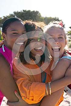 Portrait of happy diverse female friends embracing and smiling at beach, with copy space