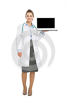 Portrait of happy doctor woman showing laptop blank screen