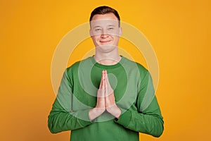 Portrait of happy dreamer guy hands together plead ask help on yellow background