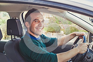 Portrait of happy driver in car. Smiling young man looking at camera.