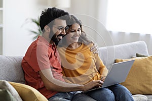 Portrait Of Happy Eastern Couple Browsing Internet On Laptop At Home