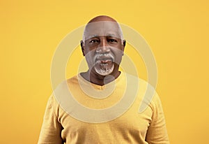 Portrait of happy elderly black man looking at camera over orange studio background