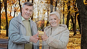 Portrait of happy elderly caucasian family wife husband senior grandparents stand outdoor in autumn park smiling old