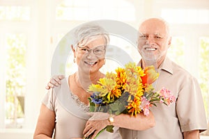 Portrait of happy elderly couple with flowers