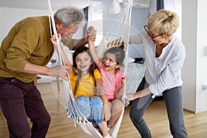 Portrait of happy elderly couple and grandchildren playing together