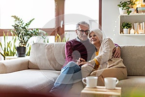 Happy elderly couple relaxing together on the sofa at home photo