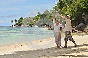 Portrait of happy elderly couple resting on beach dancing