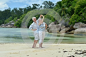 Portrait of happy elderly couple resting on beach dancing