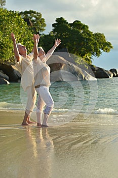 Portrait of happy elderly couple resting on beach. Travel