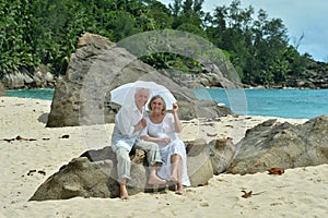 Portrait of happy elderly couple resting on tropical beach